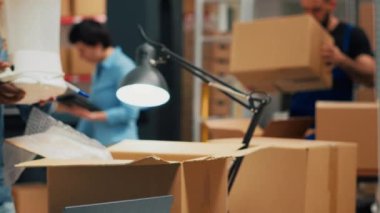 Male employee checking supply chain and doing quality control, working on business development to send products to clients. Young adult planning order shipment with merchandise. Handheld shot.
