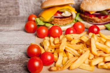 Cheeseburgers and french fries on wooden plate next to fries. Fast food. Unhealthy snack