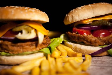Classic cheeseburgers on wooden plate next to fries. Fast food. Unhealthy snack