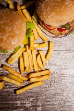 Classic cheeseburgers on wooden plate next to fries. Fast food. Unhealthy snack