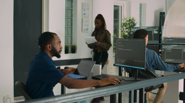 Bilgisayarda kod yazmak ve sistem bilgilerini görüntülemek için dizüstü bilgisayar kullanan Afrikalı Amerikalı geliştirici. Yazılım ajansındaki kullanıcı arayüzü üzerinde çalışan veritabanı kodlayıcı ayrıştırma algoritması.