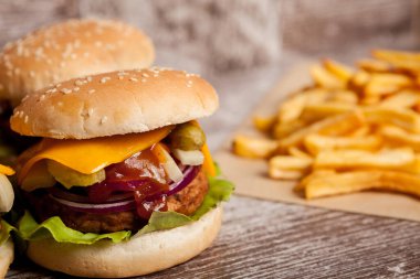 Home made cheeseburgers on wooden plate next to fries. Fast food. Unhealthy snack