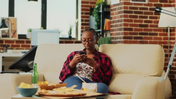 Afroamerykanka Przeglądająca Internet Smartfonie Oglądająca Ulubiony Program Telewizyjny Domu Młoda — Wideo stockowe