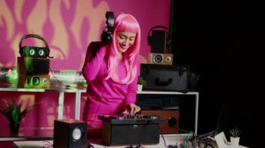 Musician using cutting-edge technology to remix music, listening song using headphones while performing in club at night time. Performer standing at dj table playing with professional mixer