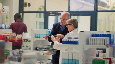 Yaşlı bir müşteri ilaç ürünleri hakkında uzmanla konuşuyor, reçete kağıdında hap arıyor. Son sınıf öğrencisi eczacıyla hastalık ve tedavi hakkında konuşuyor, eczane perakendecisi.