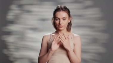 Beauty model using moisturizing face cream for skincare routine, creating ad campaign for natural products. Happy flawless woman posing on camera to promote nourishing uplifting look.