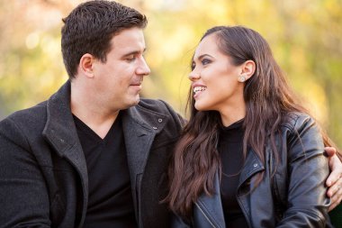 Close up of happy beautiful in love couple sitting on a bench in autumn park