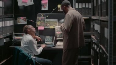 Afro-Amerikan hukuk ajanları evrak ve dizüstü bilgisayarlarda dava kanıtıyla çalışıyorlar. İfadelerini okuyorlar ve geçmişlerini araştırıyorlar. İki özel dedektif suç kayıtlarını inceliyor. El kamerasıyla..