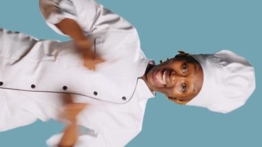 Vertical video: Excited positive woman giving thumbs up on camera, earing kitchen apron and expressing like or approval symbol. Professional restaurant chef showing agreement gesture and success.