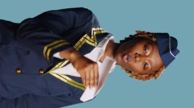 Vertical video: Young stewardess playing with paper airplane, having fun showing origami small plane on camera. Air hostess in flying uniform holding folded aviation aircraft, female model with