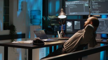 Gülümseyen kodcu programlama başarısından memnun, geceleri yeni kullanıcı arayüzü geliştiriyor. Genç yetişkin bilişim başarısını kutluyor ve neşeli ya da memnun oluyor..