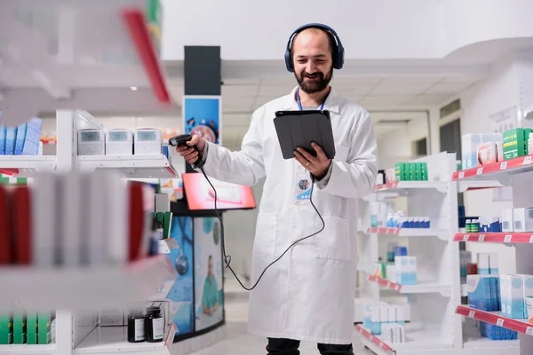 Apoteker Dengan Musik Headset Mendengarkan Sambil Memindai Kode Paket Pil — Stok Foto
