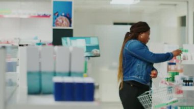 Woman taking medicaments off of drugstore shelves, looking at medical products to buy prescription medicine. Young customer checking leaflets of supplements and pills, retail store.