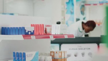 Müşteri eczane raflarındaki ürünleri alıyor, reçeteli tedavi için tıbbi ilaçlara bakıyor. Vitamin ve kutu kutu hapları kontrol eden genç bir kadın. El kamerasıyla..