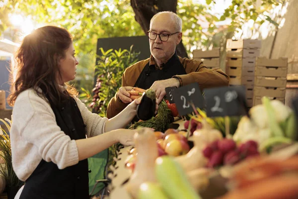 在户外粮食市场一起工作的同时 农民家庭夫妇把农场新鲜的有机水果和蔬菜放在农产品架上 小企业和健康食品概念 — 图库照片