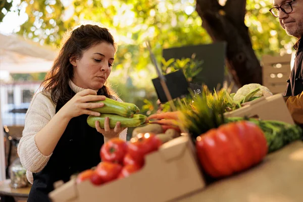 年轻妇女有机水果和蔬菜商店店主准备在当地农贸市场工作一天 女农民将Zucchini放在农产品摊上 销售健康的当地种植的食品 — 图库照片