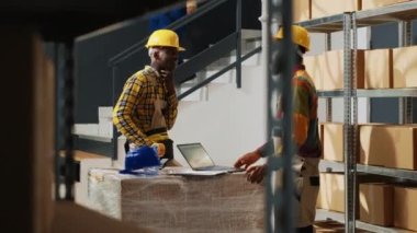 Young depot workers laughing and making jokes while the work on shipping retail store merchandise. Production team of people having funin storage room, being cheerful at work.