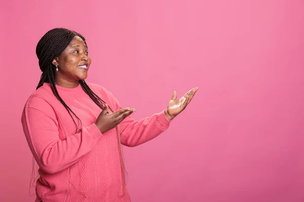 在演播室里为促销产品做广告的微笑女性形象 在粉红背景下做广告 有自信的模特 有时髦的发型 在拍摄广告时看着相机 — 图库照片