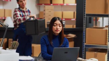 Asyalılar depodaki mal stoklarını inceliyor, depolama odasındaki perakende ürünlerin kalitesine bakıyor. Girişimci ve çalışan hisse senedi lojistiği, küçük işletmeler üzerinde çalışıyor.