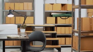 Ofis masası ve stokları olan depo müşterilere envanter ve nakliye ürünleri siparişi verecek. Depo raflarında karton paketler ve kutularla dolu boş bir depo..