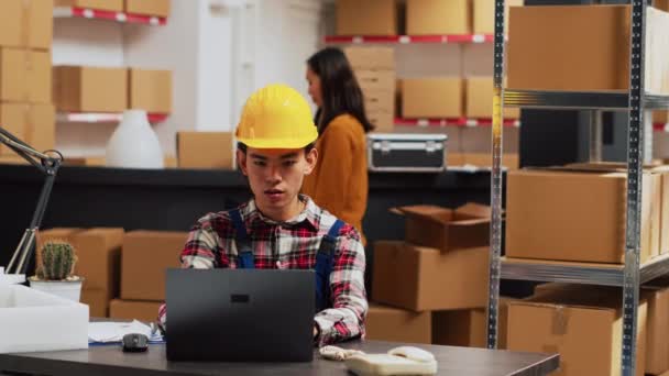 棚から倉庫用品をチェックするアジア人は ラップトップ上の在庫に取り組むためにサプライチェーンの生産を使用しています スタートアップビジネス開発のための出荷を計画する若い男 — ストック動画