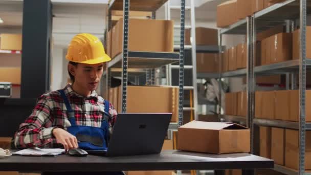 倉庫での出荷を計画してる若い男在庫物流をするためにノートパソコンを使って 製品や商品を扱う保管室の従業員 サプライチェーンの流通パック — ストック動画