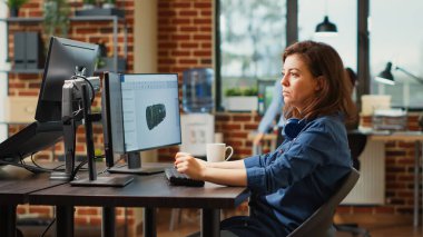 Female engineer working on turbine component development, using professional manufacturing software. Agency employee developing 3d engine component with infographics, creative skills.