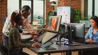 Game industry developers working on artistic development design with multiple displays on desk. Team of production department employees developing artificial intelligence technology.