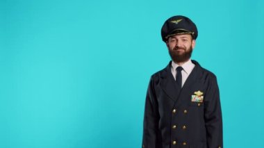 Havacı erkek pilot kamerada baş parmağını kaldırıyor, iyiye işaret ve onay veriyor. Uçuş ekibi kaptanı, uçuş üniformalı. Kabul ediyor ve kabul ediyor. Stüdyoda iyi bir sembol..