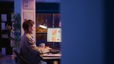 Çevrimiçi raporlara veri yazan ve finansal kalkınma planlayan, geceleri iş büyümesi üzerinde çalışan bir şirket çalışanı. Kadın yönetici masadaki grafik analizlerini analiz ediyor. El kamerasıyla..