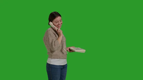 喜びの少女は 固定電話の呼び出しでチャットの側のビューでは コードの画面上に立って電話を使用しています コード付きのオフィス電話を使用して笑顔の女性 緑の画面を背景にレジャー活動 — ストック写真