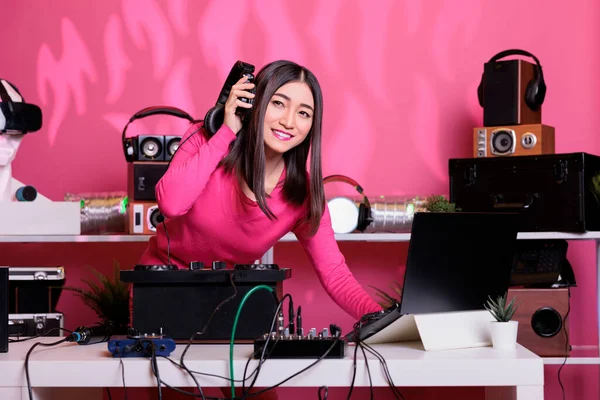 亚洲音乐家戴着耳机 在粉红背景的工作室里用专业的转盘演奏电子音乐 Dj用电子设备和话筒播放立体声 — 图库照片