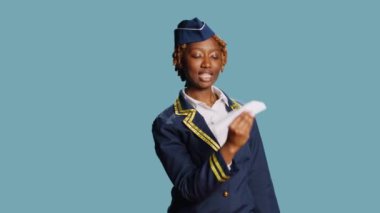 Neşeli aptal hostes kağıt uçakla oynuyor, stüdyoda origami küçük uçakla eğleniyor. Havacılık üniformalı genç bir pilot katlanmış bir uçak tutuyor, kendine güvenen bir model..