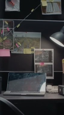 Dikey video: Polis arşivindeki masasında ipuçları olan dedektif panosu, duvardaki olay yeri fotoğrafları ve soruşturma ofisindeki dava dosyaları. Adli kanıtlarla dolu boş olay odası ve...