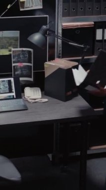 Dikey video: Özel ajans dedektifi harita ve önemli ipuçlarıyla soruşturma yürütüyor, olay odasındaki kamera görüntülerini ve adli kanıtları inceliyor. Dava dosyalarını kullanan kadın ajan.