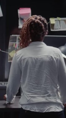 Dikey video: Hukuk bürosu dedektifi arşivdeki suç kayıtlarını okuyor, şüpheli fotoğrafları inceliyor ve ipuçları buluyor. Kadın araştırmacı, suç davasıyla ilgili dosyayı tutuyor, şüpheli geçmişi araştırıyor.