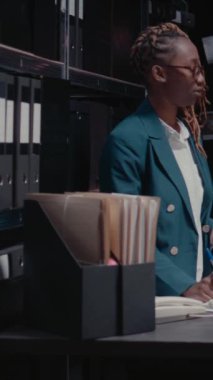 Dikey video: Afro-Amerikan ajanları olay odasındaki raporları okuyor, güvenlik kamerası görüntüleriyle şüpheliyi bulmaya çalışıyorlar. Özel dedektifler dedektif haritasındaki adli delilleri inceliyor.
