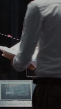 Dikey video: Erkek müfettiş arşiv odasında kanıtları analiz ediyor, tanık ifadelerini okuyor. Özel ofis şüpheli fotoğraflara bakıyor ve soruşturmadaki sabıka kayıtlarına bakıyor.