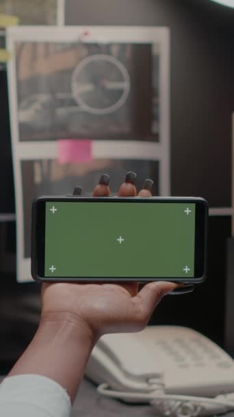 垂直录像 警察在证物室使用绿屏 展示模型展示和进行刑事调查 检查员用智能手机检查孤立的色键模板 — 图库视频影像