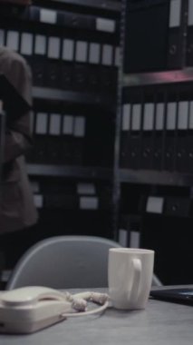 Dikey video: Erkek müfettiş arşivdeki fiziksel kanıtları analiz ediyor, sabıka kaydı olan dava dosyalarına bakıyor. Polis memuru raporları ve tanık ifadelerini okuyor. El kamerasıyla..