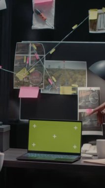 Dikey video: Masadaki dizüstü bilgisayarda yeşil ekran kullanan iki müfettiş, polis arşiv dosyalarındaki vaka raporlarını inceliyor. Özel dedektifler ekranda boş bir telif alanıyla izole ekrana bakıyor..