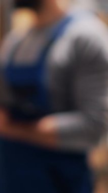 Dikey video: Depo amiri elinde stok lojistik listesiyle dizüstü bilgisayar tutuyor, mal paketlerine bakıyor ve sipariş dağıtımını planlıyor. Kalite kontrol için bilgisayar kullanan bir erkek çalışan. El kamerasıyla..