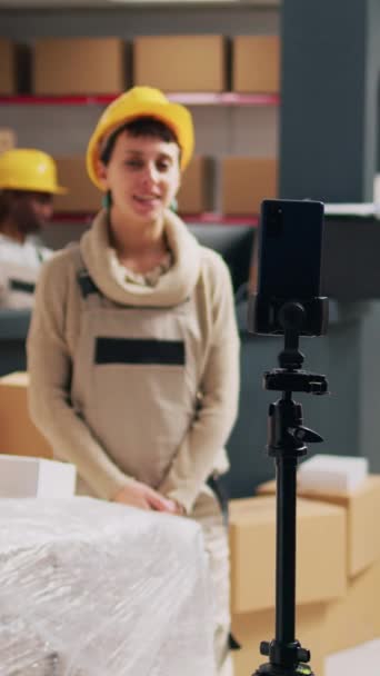垂直视频 主管在仓库记录广告视频 在社交媒体应用程序上显示商品包 仓库员工使用智能手机拍摄公关广告 储物柜 — 图库视频影像