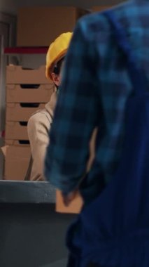 Dikey video: Kadın çalışan, hisse senedi lojistiği için barkodları tarıyor, nakliye ve envanter çalışmalarından önce tarayıcı kullanarak ürünü kontrol ediyor. Depoda sipariş dağıtımı planlayan kişi