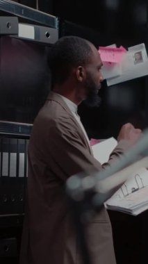 Dikey video: Özel dedektif gemideki delillere bakıyor ve polis raporlarını suç dosyalarıyla karşılaştırıyor. Dedektifin elinde adli kanıtlarla birlikte tuttuğu klasör.