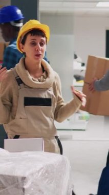 Dikey video: Depoda ürün kutularını çevrimiçi sosyal medya sayfasında gösteren genç yetişkin reklam videosu. Depo çalışanları halkla ilişkiler ve endüstriyel ürünleri kaydetmek için cep telefonu kullanıyor..