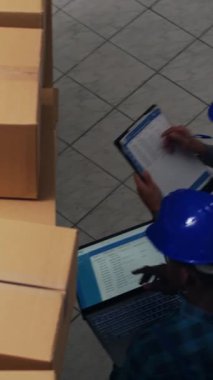 Dikey video: Endüstriyel ürünlerle çalışan iki kadın, dijital tabletle ürün sevkiyatı planlıyor. Depoda envanter sayımı yapan, ürün üreten bir ekip..