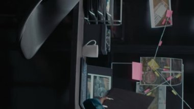 Dikey video: Polis dedektifi suç mahallinden ipuçlarını inceliyor, arşiv ofisindeki gözetim fotoğraflarıyla birlikte kanıt haritasına bakıyor. Şüpheli geçmişini araştıran özel dedektif..