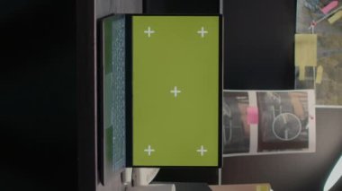 Dikey video: Erkek ve kadın bilgisayarda yeşil ekranla çalışıyor, suçu çözmek için kanıt odasında oturuyor. Dizüstü bilgisayara bakan polis memurlarından oluşan bir ekip, krom anahtar şablonunu izole edilmiş maket ekranla çalıştırıyor.