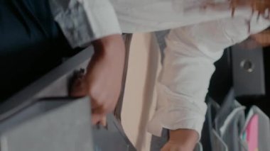 Dikey video: Kadın ajan kanıt odasında arşiv kayıtlarını okuyor, önemli bilgilerle suç üzerinde çalışıyor. Özel dedektif olay yerini ve gözetleme fotoğraflarını inceliyor. El kamerasıyla..